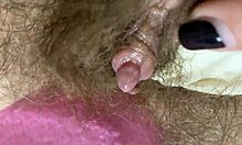 In primo piano un grosso clitoride che viene sfregato e spruzzato